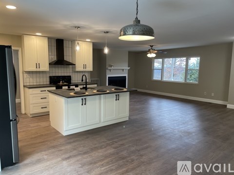 A modern kitchen with a black refrigerator and white cabinets.