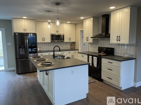 A modern kitchen with white cabinets and black appliances.