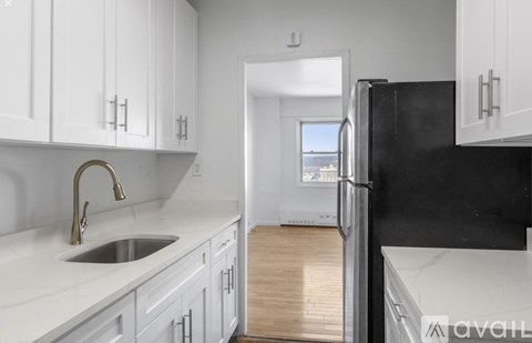 A kitchen with white cabinets and a black refrigerator.