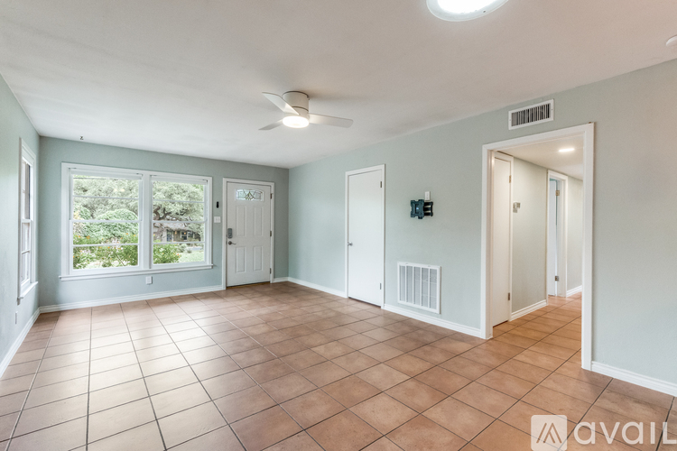A spacious room with tile flooring and a ceiling fan.
