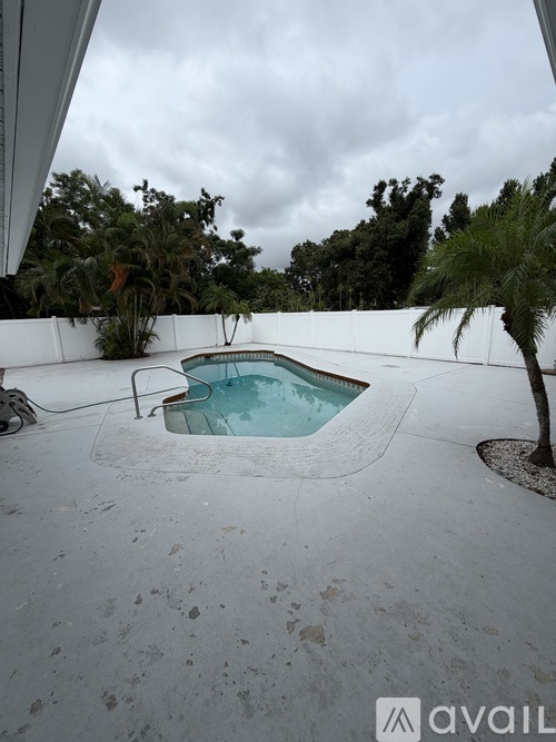 A pool surrounded by a white fence and trees.