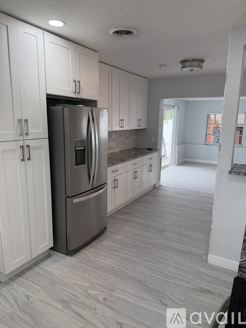 A kitchen with white cabinets and a stainless steel refrigerator.