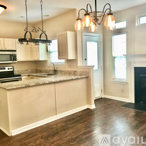 A kitchen with a granite countertop and a chandelier hanging from the ceiling.