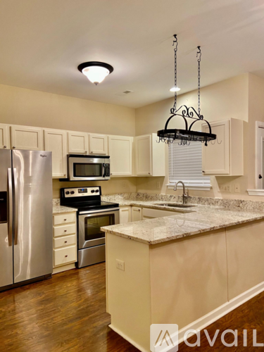 A kitchen with a refrigerator, microwave, oven, sink and cabinets.