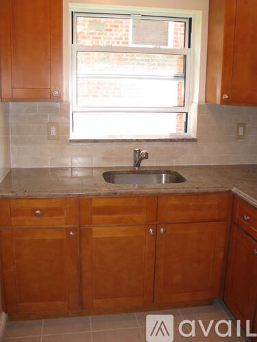 A kitchen with wooden cabinets and a window above the sink.