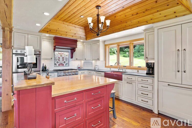 A kitchen with wooden cabinets and a red island.