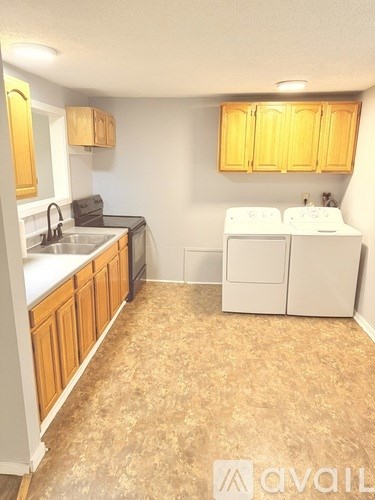 A kitchen with wooden cabinets and a washer and dryer.