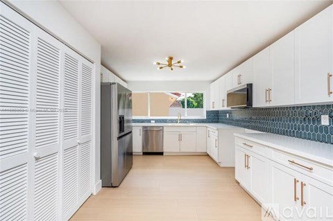 A kitchen with white cabinets and a black fridge.