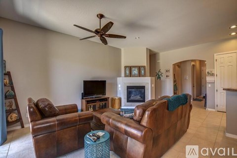 A living room with brown leather furniture and a ceiling fan.