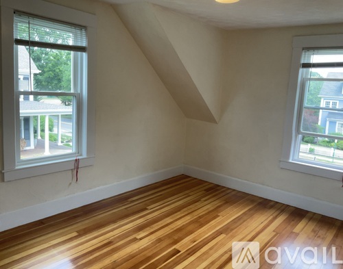 A room with wooden floors and two windows.