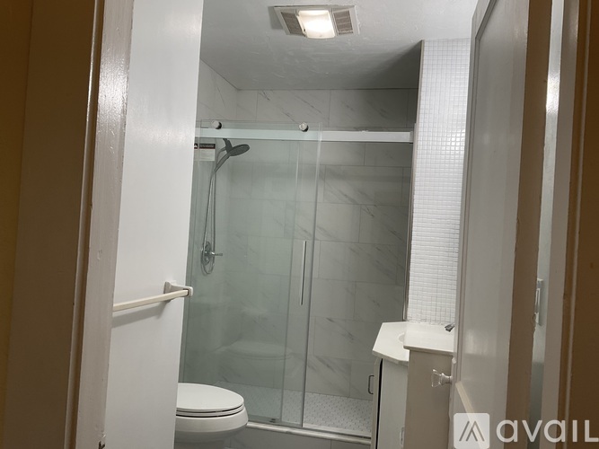 A bathroom with a toilet, a glass shower door, and a white counter.