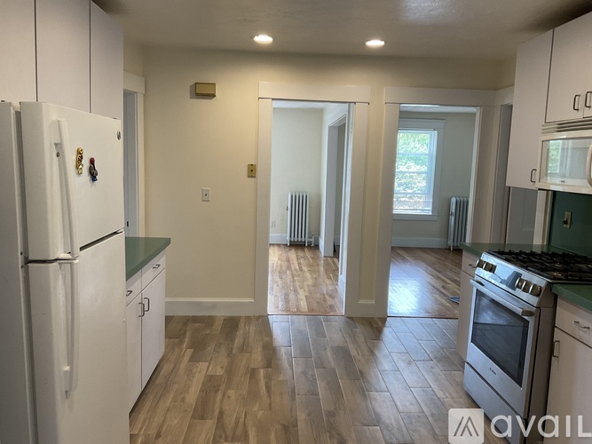 A kitchen with white cabinets and a wooden floor.