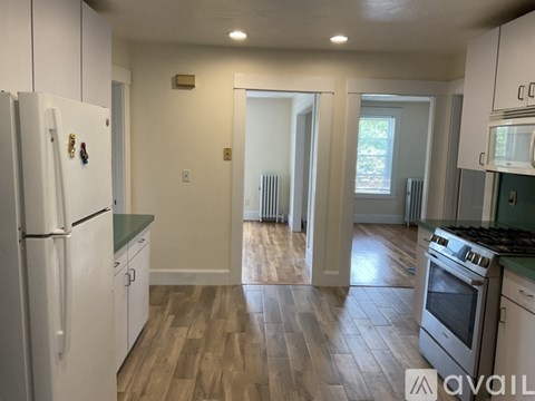 A kitchen with white cabinets and a wooden floor.