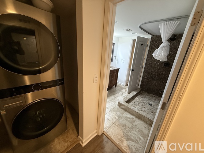A stainless steel dishwasher is in a kitchen with a white door.