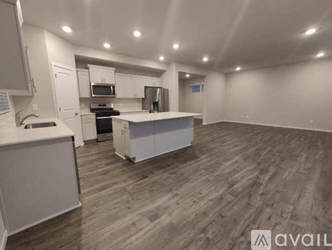 A spacious kitchen with white cabinets and a wooden floor.