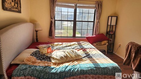 A bedroom with a large bed and a window overlooking a lawn.