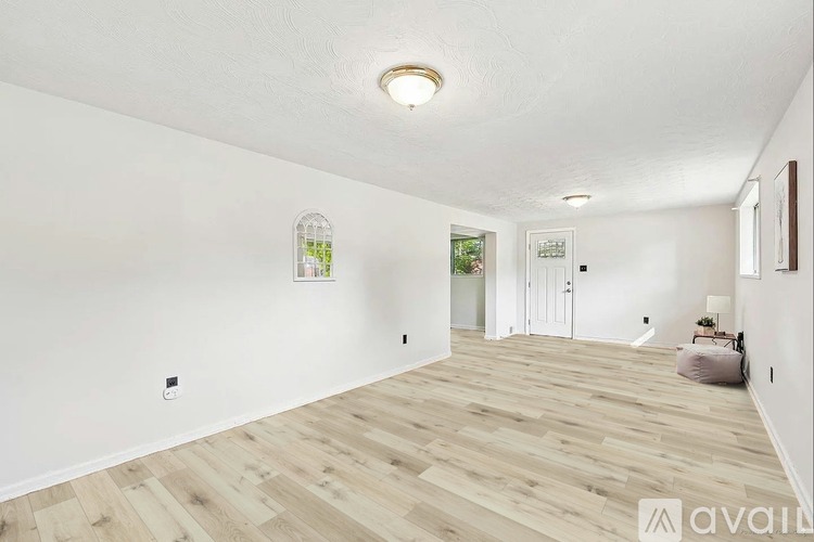 A spacious room with wooden flooring and white walls.