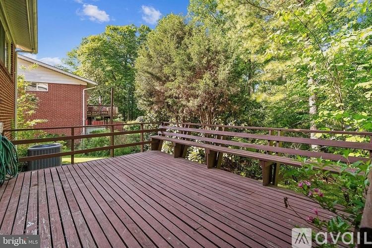 A wooden deck with a railing and trees in the background.
