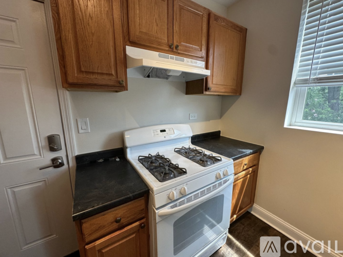 A kitchen with a white stove and black countertops.
