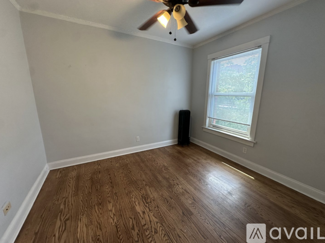 A room with a ceiling fan and a window with a view of trees outside.