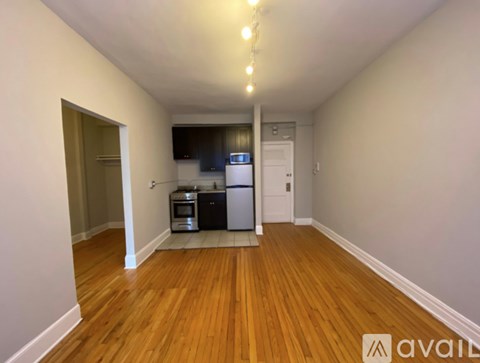A kitchen area with wooden floors and a refrigerator.