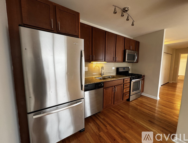 A kitchen with wooden cabinets and a stainless steel refrigerator.