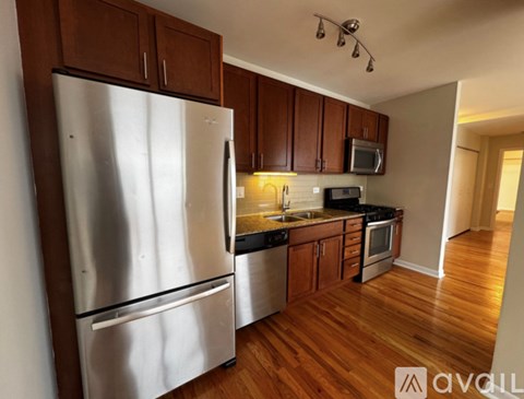 A kitchen with wooden cabinets and a stainless steel refrigerator.