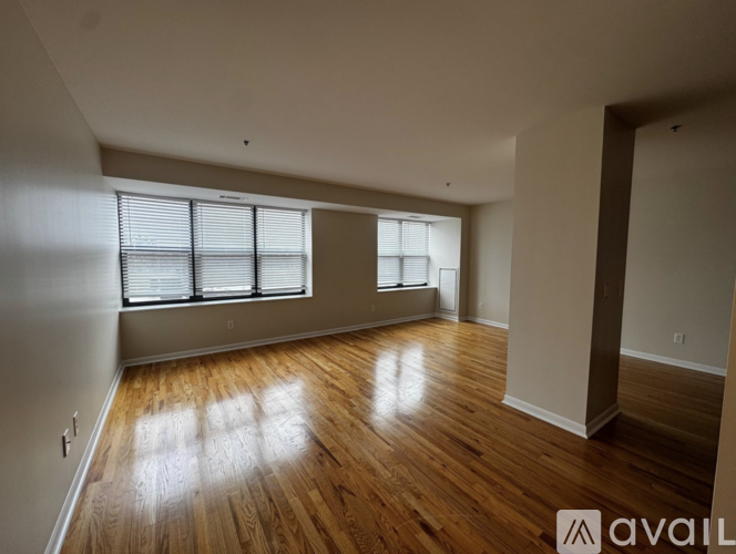 A room with wooden floors and a window with blinds.