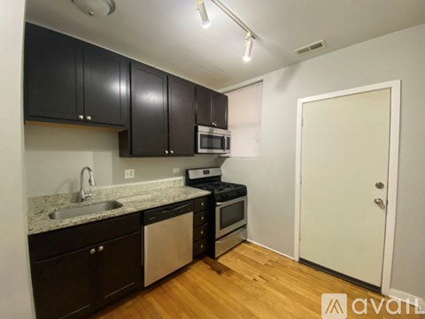 A kitchen with black cabinets and a white door.
