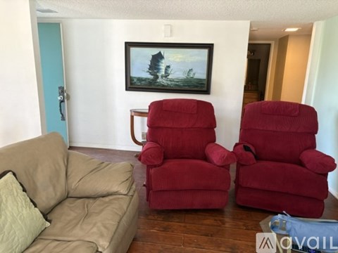 A living room with a couch, two chairs and a painting on the wall.