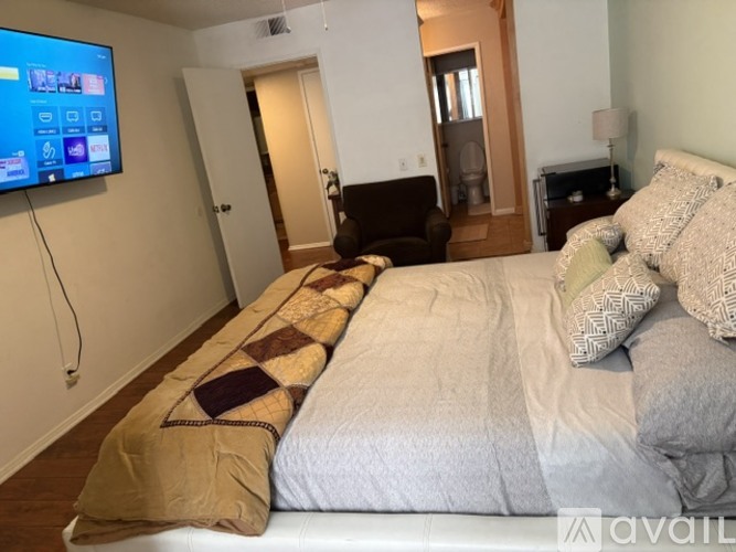 A bedroom with a large bed and a flat screen TV mounted on the wall.