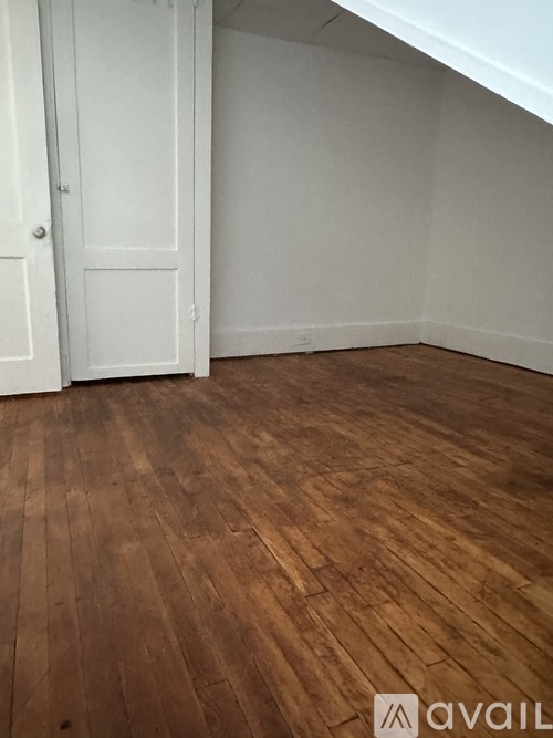 A room with a white door and wooden flooring.