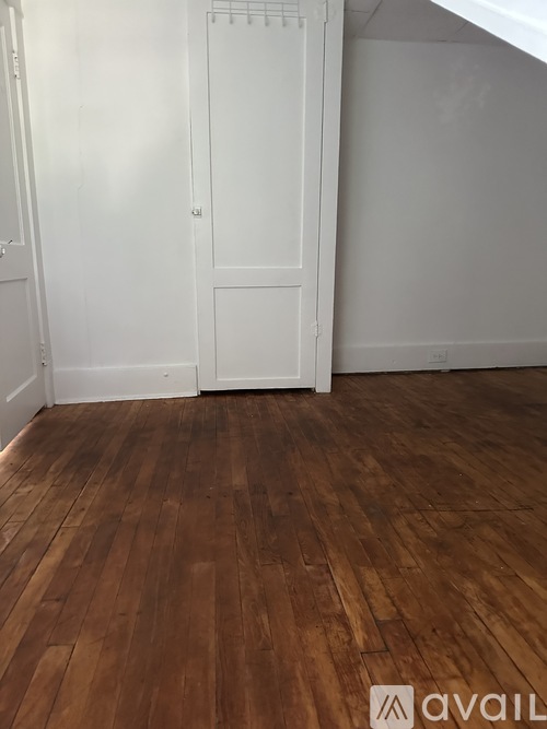 A room with wooden flooring and white walls.