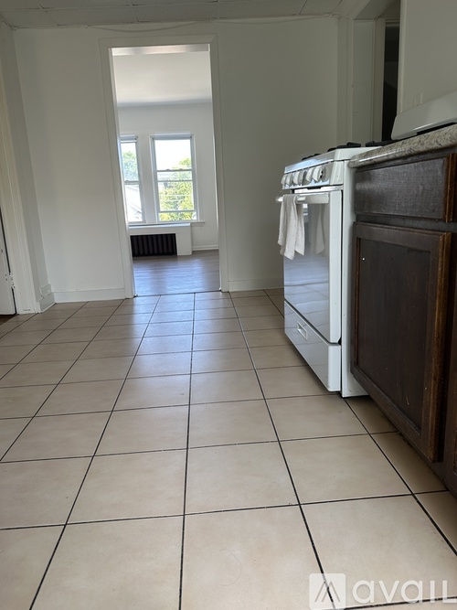 A kitchen with a white oven and tiled floor.