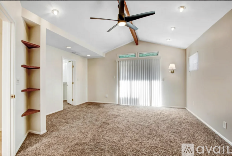 A spacious room with a ceiling fan and carpeted floor.
