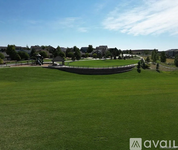 A large grassy field with a fence and some trees in the distance.