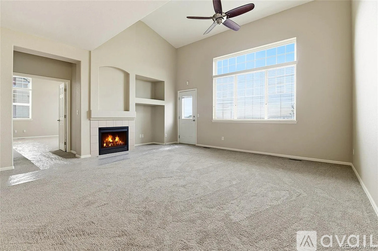 A spacious living room with a fireplace and a ceiling fan.
