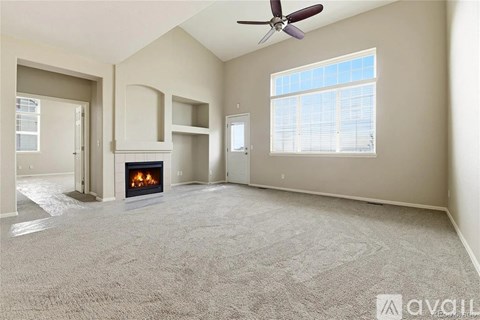 A spacious living room with a fireplace and a ceiling fan.