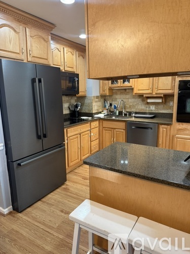 A kitchen with wooden cabinets and a black fridge.