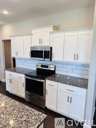 A kitchen with white cabinets and a black stove top oven.