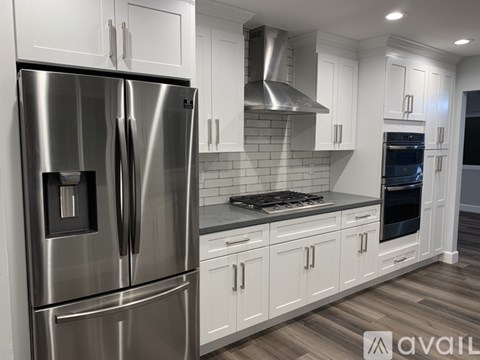 A modern kitchen with a stainless steel refrigerator and white cabinets.