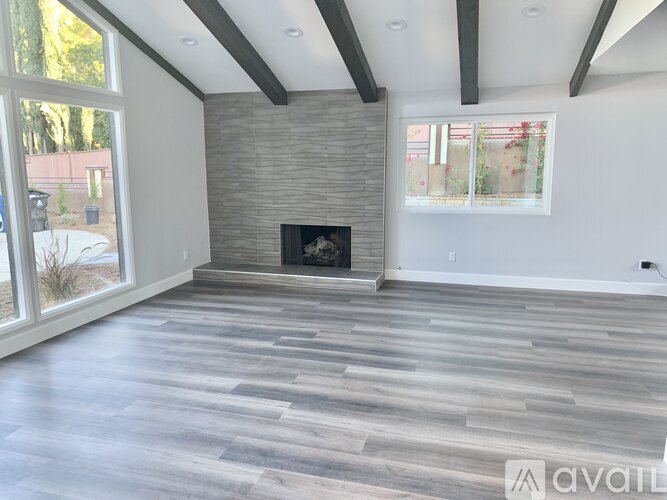 A spacious living room with a fireplace and large windows.