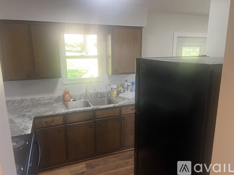 A kitchen with wooden cabinets and a black refrigerator.