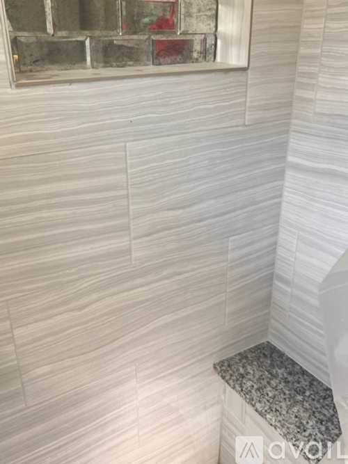 A bathroom with a marble bench and a tiled wall.