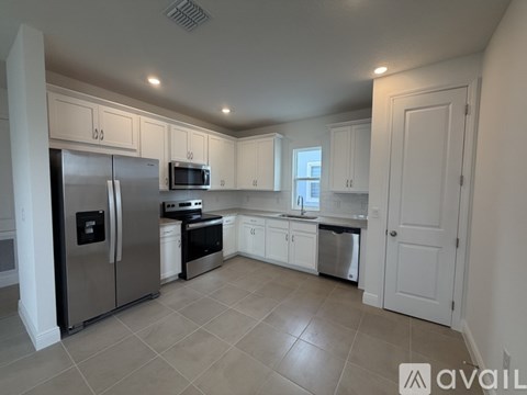 A kitchen with white cabinets and a stainless steel refrigerator.