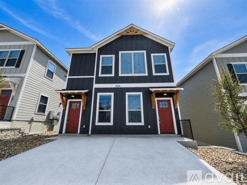 A modern two-story house with a black and white exterior and red doors.