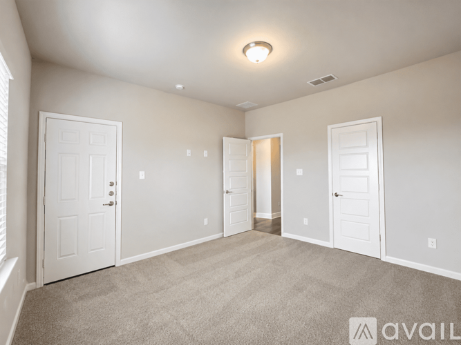 A spacious room with white doors and carpeted floor.