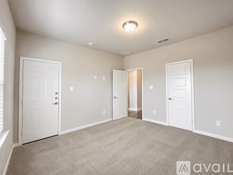 A spacious room with white doors and carpeted floor.