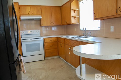 A kitchen with wooden cabinets and a black refrigerator.