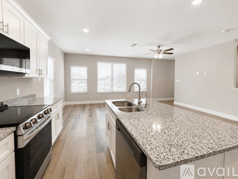 A kitchen with a granite countertop and a black stove top oven.